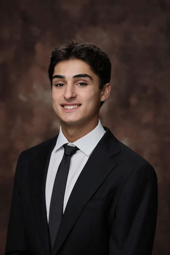 Joshua Niku, the founder of Instaclot, smiling in a dark suit and tie.